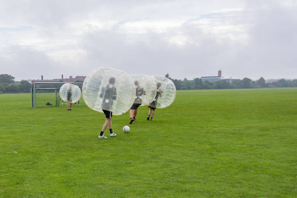 Four men playing soccer in a bumperball stock photo