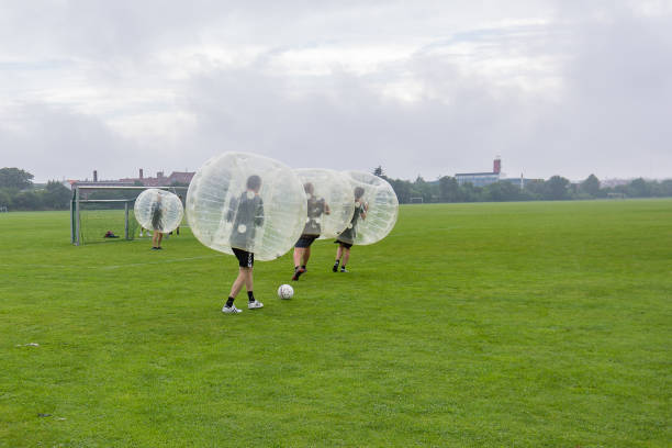 Four men playing soccer in a bumperball Four men playing soccer in bumper balls on a green lawn, a new funsport in Copenhagen, Denmark - July 27, 2017 inflatable soccer balls stock pictures, royalty-free photos & images