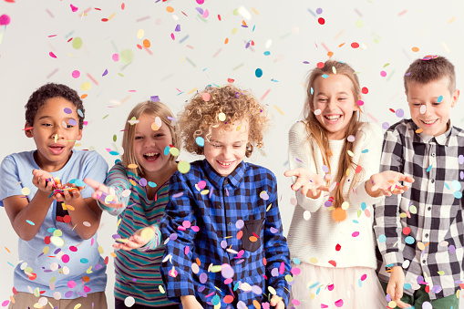 Group of sweet young kids catching colorful confetti
