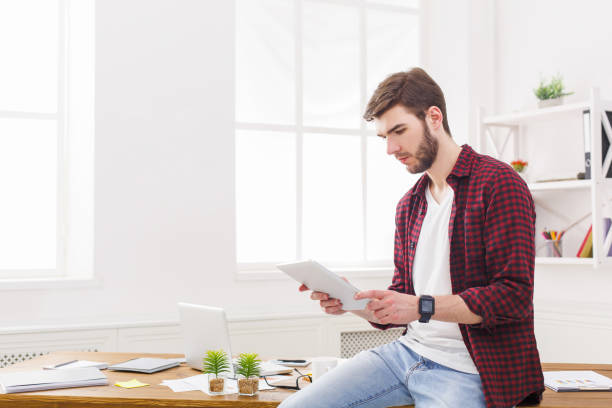 istock Pensive young businessman using digital taplet in office 836578806