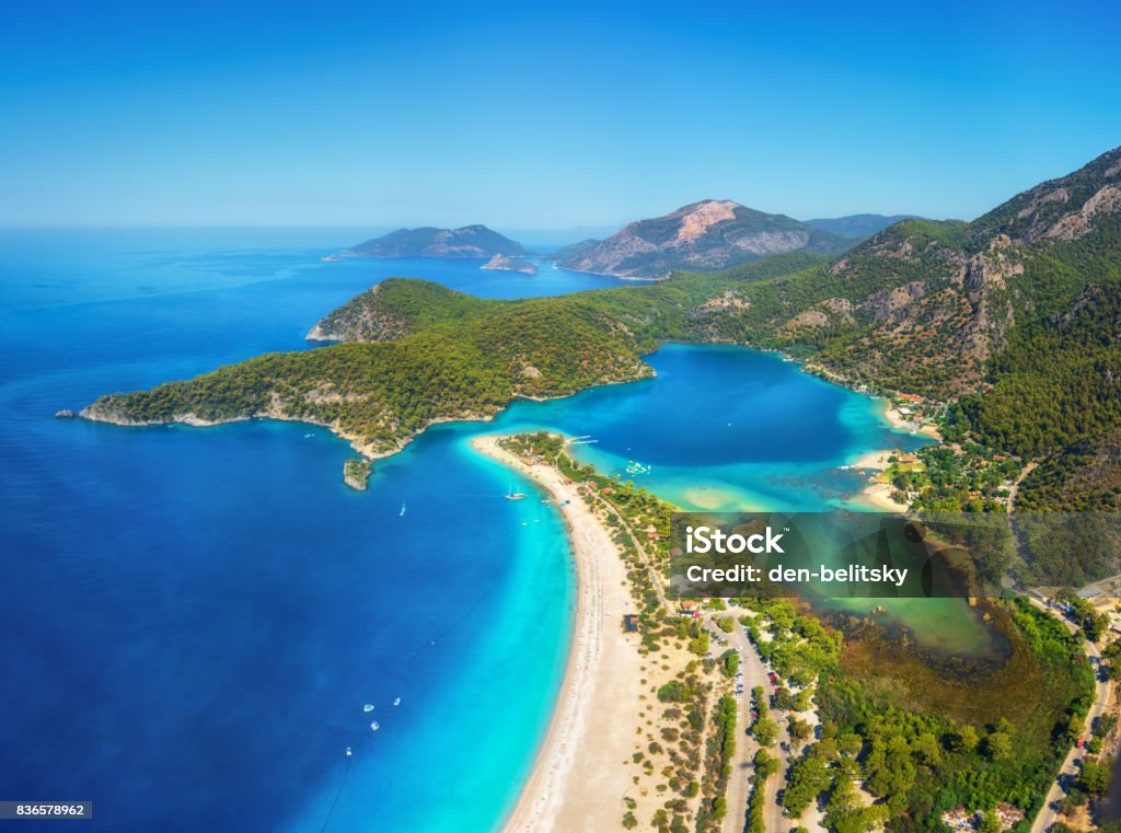 Incredibile vista aerea della Laguna Blu a Oludeniz, in Turchia. Paesaggio estivo con montagne, foresta verde, acqua azzurra, spiaggia sabbiosa e cielo blu in una luminosa giornata di sole. Sfondo di viaggio. Vista dall'alto. natura - Foto stock royalty-free di Oludeniz