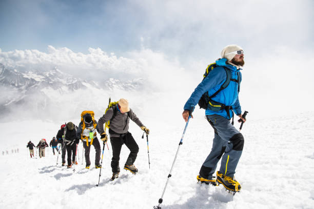 雪に覆われた山の頂上に登る登山家たちのグループ - snow hiking ストックフォトと画像