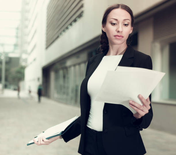 mujer está examinando documentos - success signing businesswoman serious fotografías e imágenes de stock