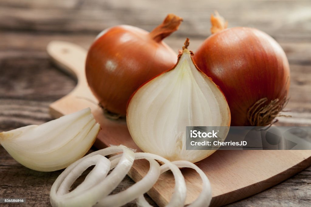 Fresh healthy onions on chopping board Fresh healthy onions and one sliced onion on chopping board Onion Stock Photo