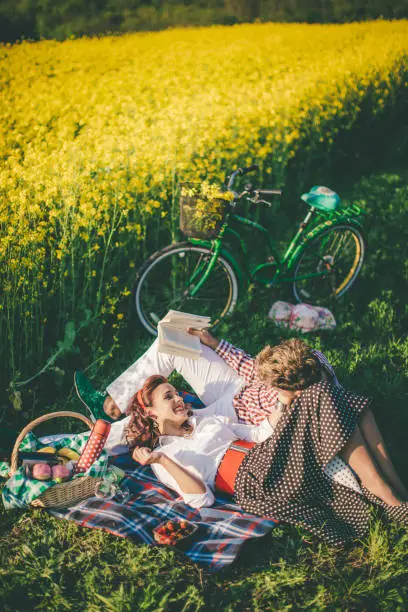 Happy couple laughing while reading book at picnic