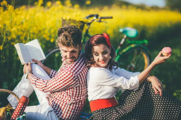 Happy couple laughing while reading book at picnic