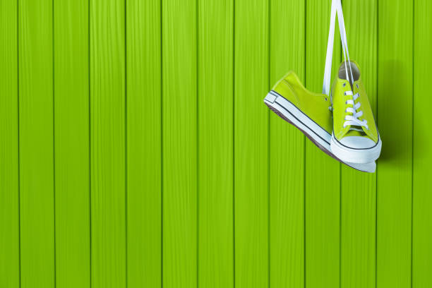 Pair of new green sneakers hanging on wooden wall