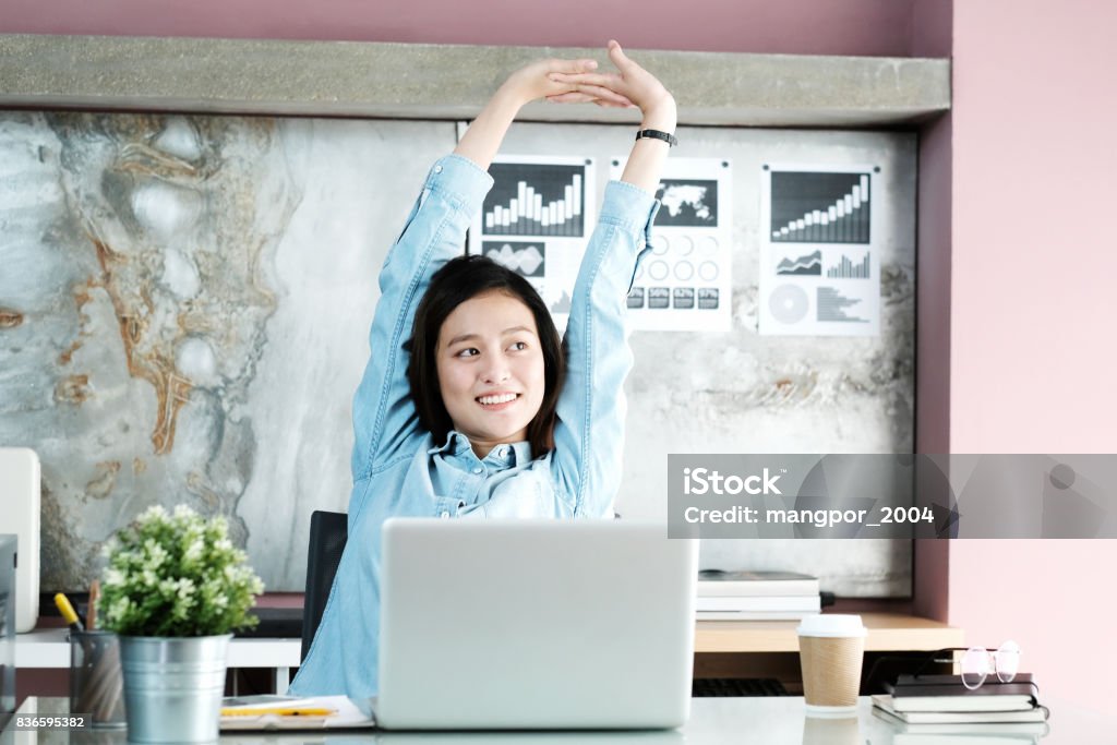 Office woman stretching body for relaxing while working with laptop computer at her desk, office lifestyle, business situation Stretching Stock Photo