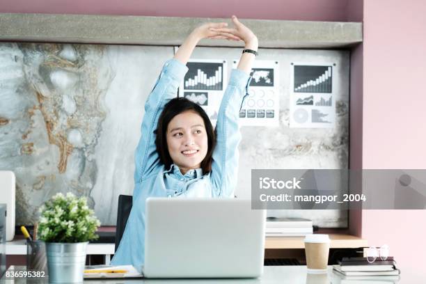 Office Woman Stretching Body For Relaxing While Working With Laptop Computer At Her Desk Office Lifestyle Business Situation Stock Photo - Download Image Now