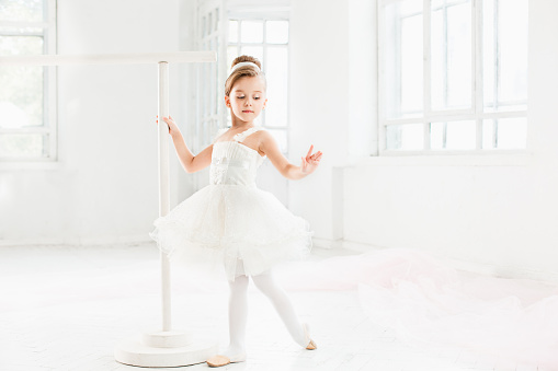 Little ballerina girl in a tutu. Adorable child dancing classical ballet in a white studio. Children dance. Kids performing. Young gifted dancer in a class. Preschool kid taking art lessons.