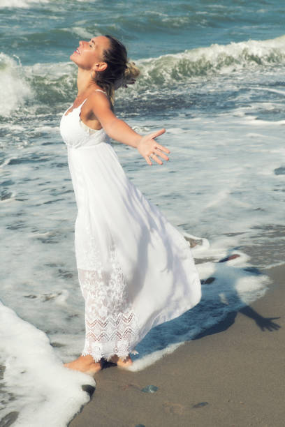 istock blond woman by the ocean and spreading her arms 836619406