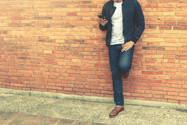 istock Smart man standing with holding smartphone on wall background. 836622322
