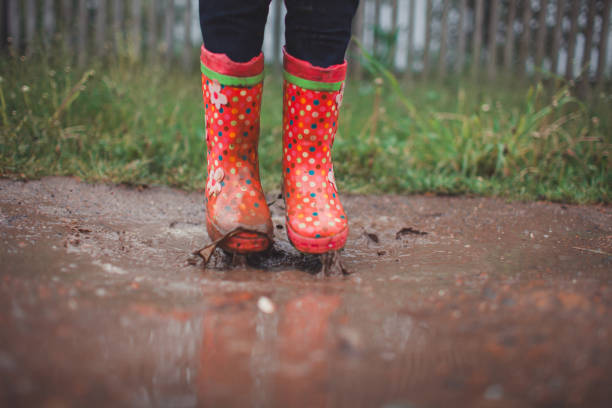 istock Little girl jumping on puddle in rubber boot 836630278