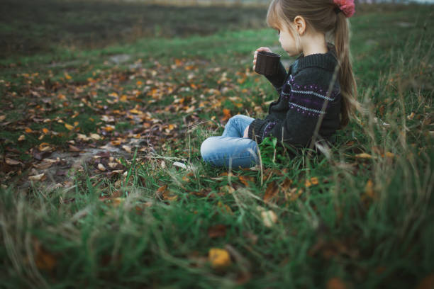 istock Little girl sitting on grass and drinking tea 836630458