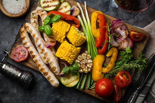 Barbeque sausages with vegetables on rustic background