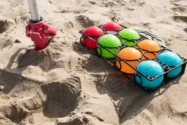 Set of colorful bowls for beach play lay on sand close to umbrella