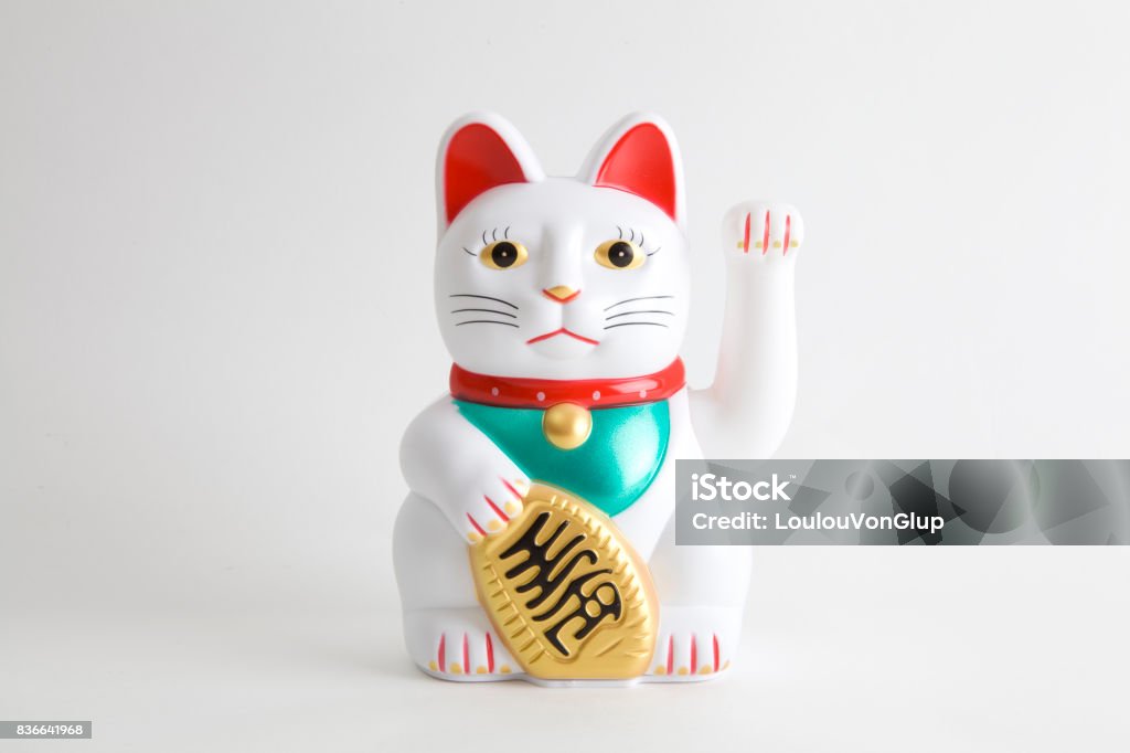 Maneki-neko white a Maneki-neko plastic cat, Symbolizing luck and wealth, on a white background Domestic Cat Stock Photo