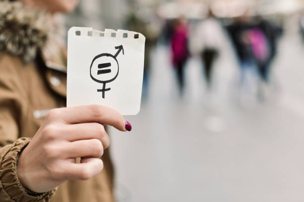 woman with a symbol for gender equality closeup of a young caucasian woman in the street showing a piece of paper with a symbol for gender equality drawn in it gender equality stock pictures, royalty-free photos & images