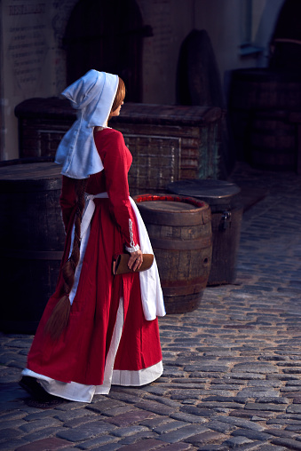 Townswoman en vestido rojo con un delantal y un acompañante en la calle. Traje estilizado del más adelante edades medias en 15 / siglo XVI. photo