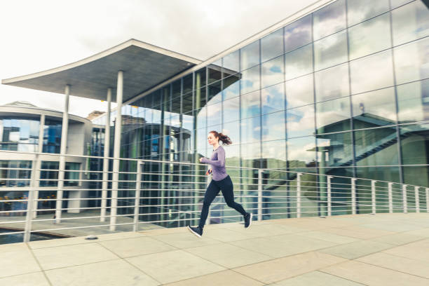 istock Woman jogging, panning view with modern buildings on background 836648884