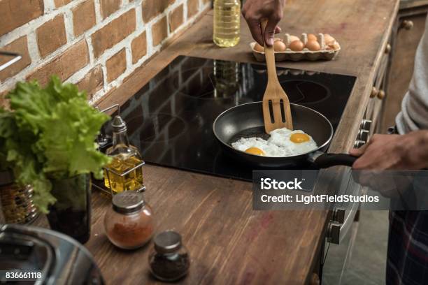 Partial View Of Young Man Preparing Eggs For Breakfast In Kitchen At Home Stock Photo - Download Image Now