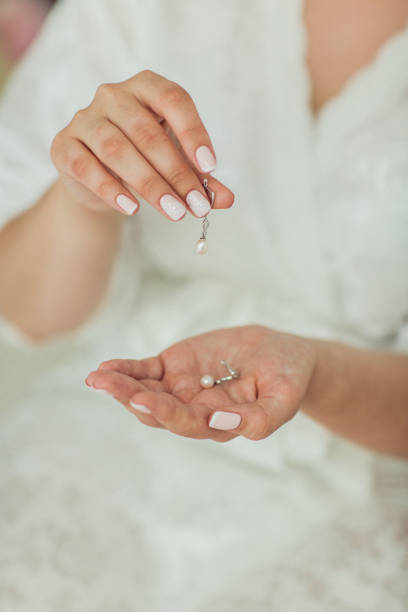 istock Elegant bride holding silver earrings. Tender hands with jewelry. 836661346