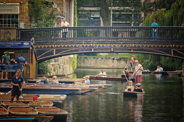 Punt hire on the River Cam A group of tourists hiring punts and either returning or leaving with their punts from Scudamore's punt hire company on the River Cam in Cambridge, England. Cambridge is famous for punts and is one of the two premiere University towns in the UK. couple punting stock pictures, royalty-free photos & images