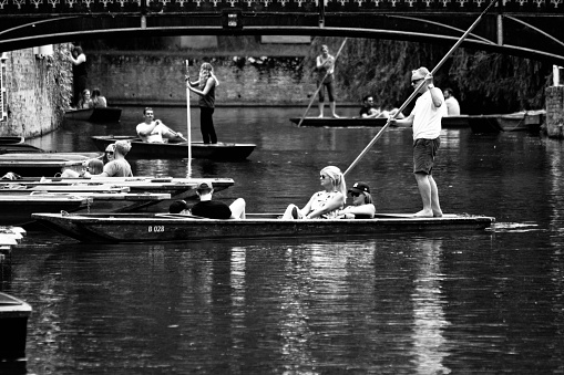 A group of tourists hiring punts and either returning or leaving with their punts from Scudamore's punt hire company on the River Cam in Cambridge, England. Cambridge is famous for punts and is one of the two premiere University towns in the UK.
