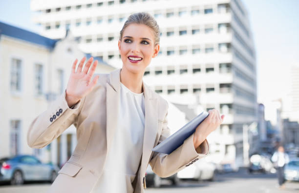 istock Smiling gorgeous businesswoman holding tablet pc waving 836662848