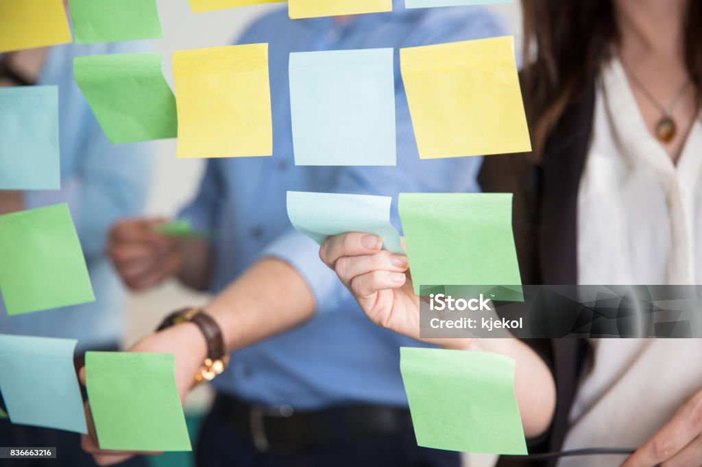 Meio de negócios pessoas furando notas adesivas em vidro - Foto de stock de Papel Adesivo royalty-free