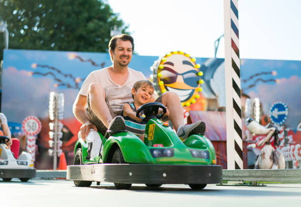 3 year old boy and father looking very happy on go-cart in amusement park