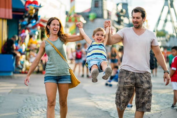 happy family enjoying summer day in amusement park three years old boy with happy smiling mom and dad having fun on summer vacation day in themepark amusement park stock pictures, royalty-free photos & images