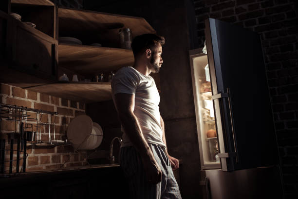 istock side view of bearded young man in pajamas looking at open refrigerator at night 836666746