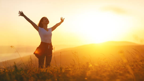 mujer feliz en puesta de sol en naturaleza hasta abrir las manos - contraluz fotos fotografías e imágenes de stock