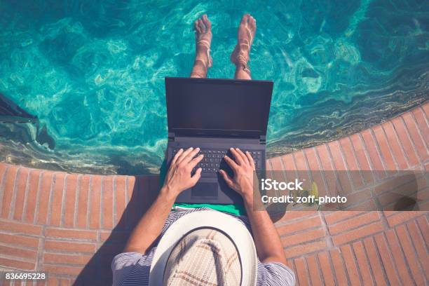 Tourist Sitting At The Edge Of Swimming Pool And Using Blank Screen Laptop Summer Vacation And Freelancer Concepts Stock Photo - Download Image Now
