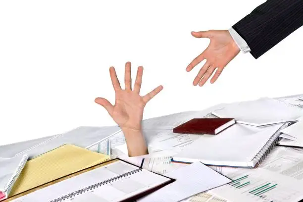 Businessman drowning in paperwork reaching for assistance and support