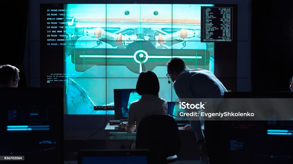 People managing flight on base Back view of man and woman in space flight control center. Docking of space modules. Aerospace Engineering Stock Photo