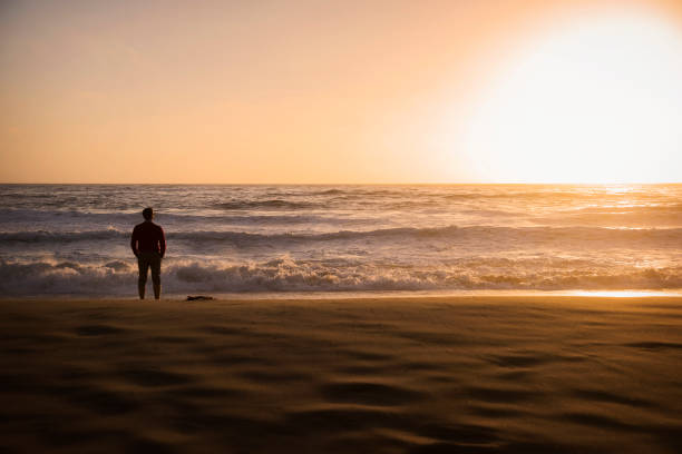 istock A young man walking on the beach at sunset 836704340