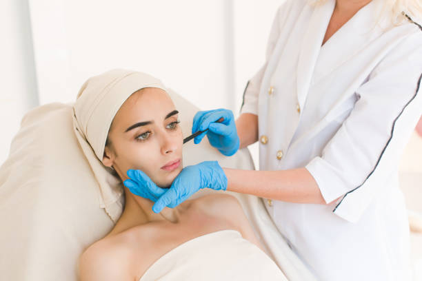 istock Doctor drawing marks on female face 836709280
