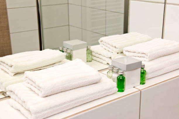 frisse witte gevouwen handdoeken met badkamer accessoire set - hotel shampoo stockfoto's en -beelden