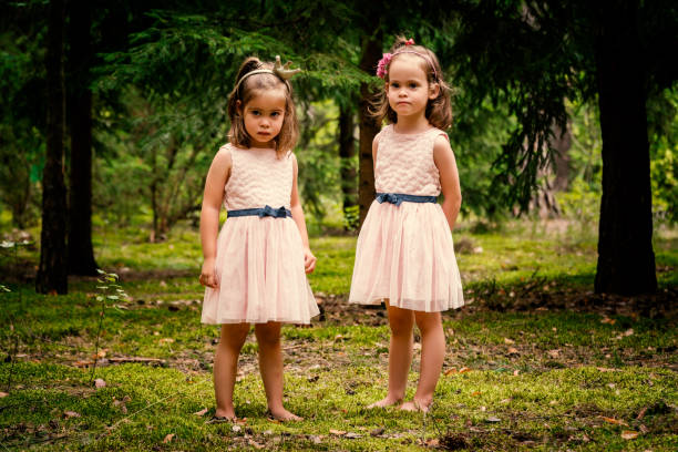 Two lovely girls in dresses posing in the summer forest