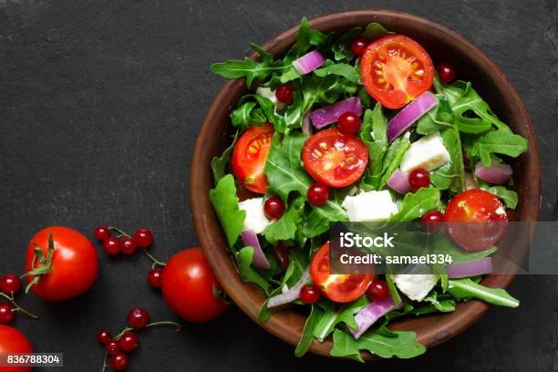 Photo libre de droit de Salade De Roquette Fromage Feta Oignon Rouge Et Aux Groseilles Rouges Dans Un Bol banque d'images et plus d'images libres de droit de Salade composée