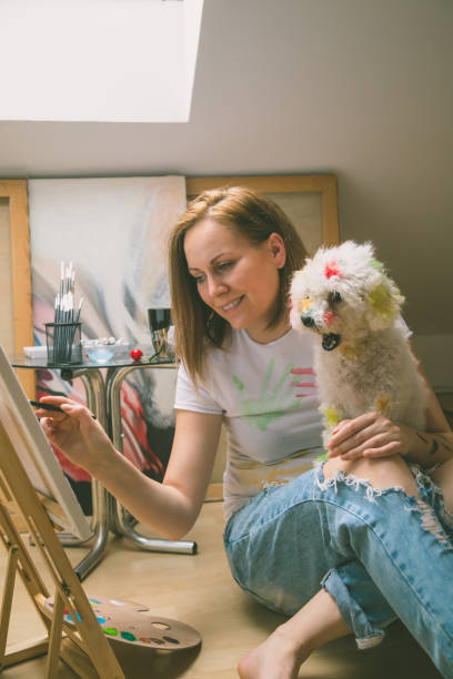 istock Happy young woman paints on canvas 836788496
