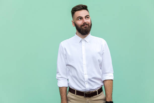 istock Flying of thoughts. Thoughtful bearded businessman looking away while standing against light green wall. Studio shot 836798032