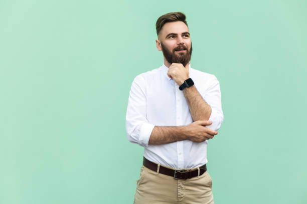 istock Thoughtful bearded businessman looking away while standing against light green wall. Studio shot 836798070
