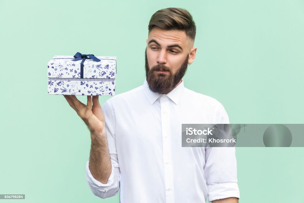 Hmm, was es ist! Bärtiger Mann Geschenkbox und wollen zu offen zu betrachten. Hellgrünen Hintergrund. Studio gedreht - Lizenzfrei Geschenk Stock-Foto