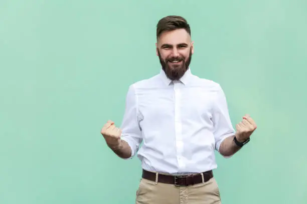 Photo of Businessman rejoicing for his success. Isolated on light green background.