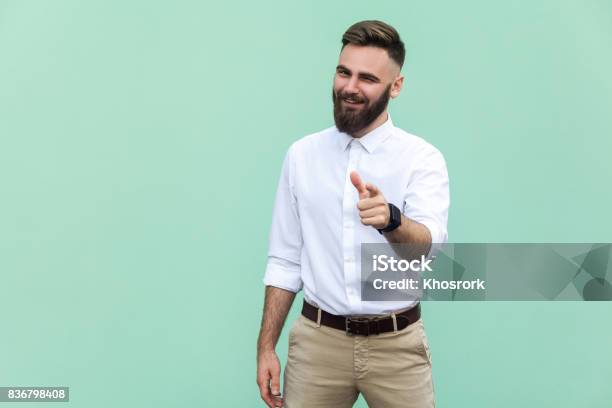 Hey You Young Adult Bearded Man Pointing Finger And Looking At Camera On Light Green Background Indoor Studio Shot Stock Photo - Download Image Now