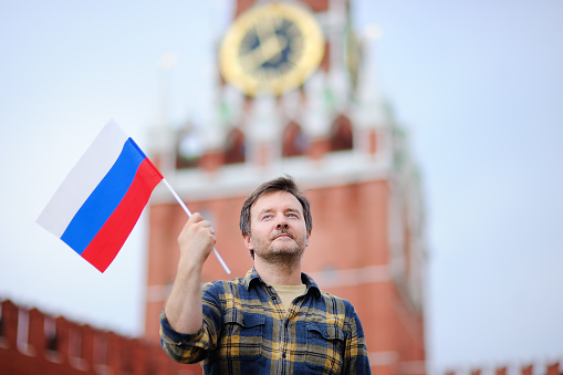 Hombre de mediana edad con bandera rusa con la torre de Spasskaya (Rusia, Moscú) sobre fondo photo