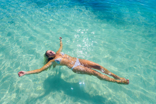 istock Woman floating on turquoise water on a tropical beach. 836810640
